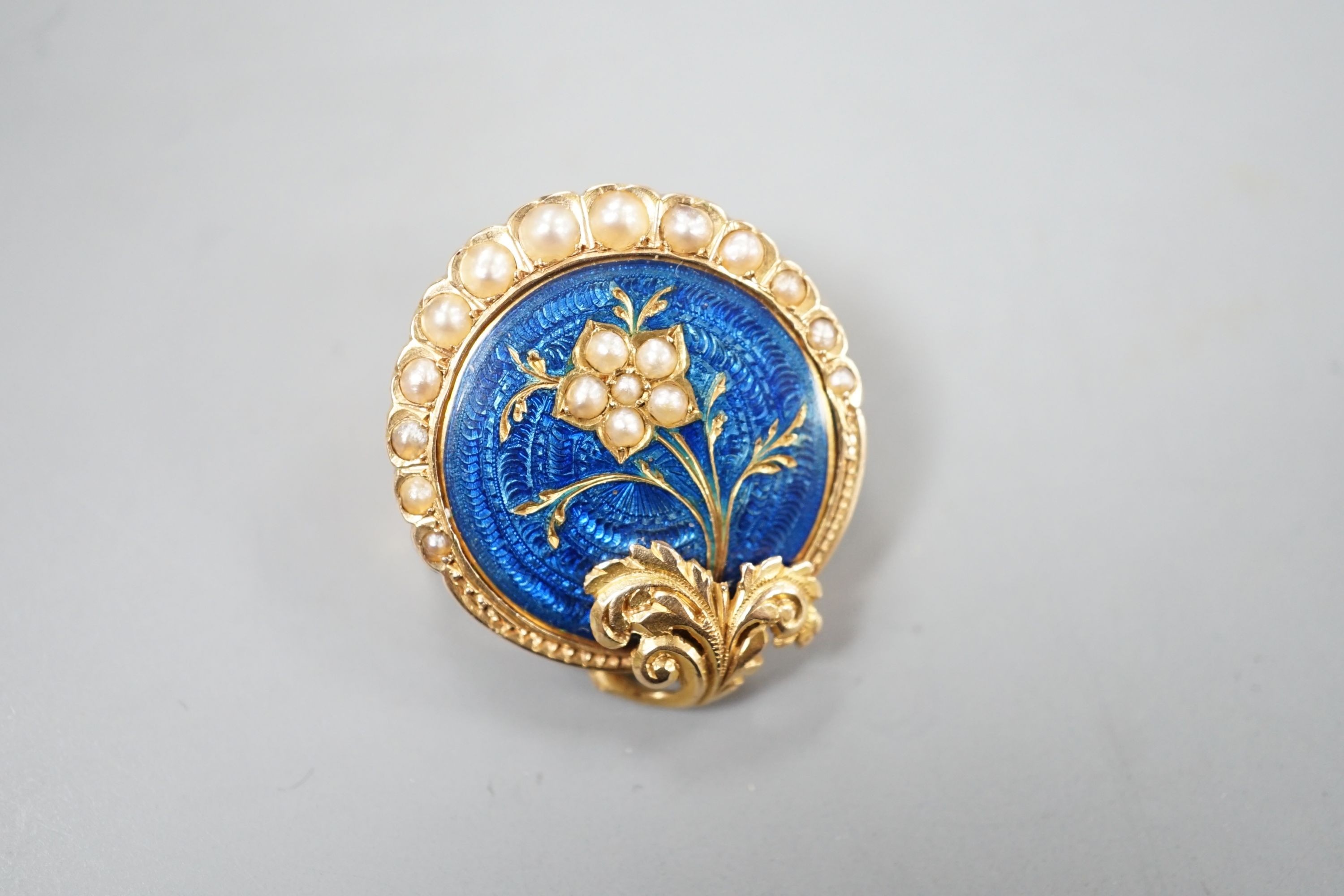 A nearly 20th century yellow metal, blue enamel and seed pearl set circular brooch, 22mm, gross 4.5 grams, in fitted box.